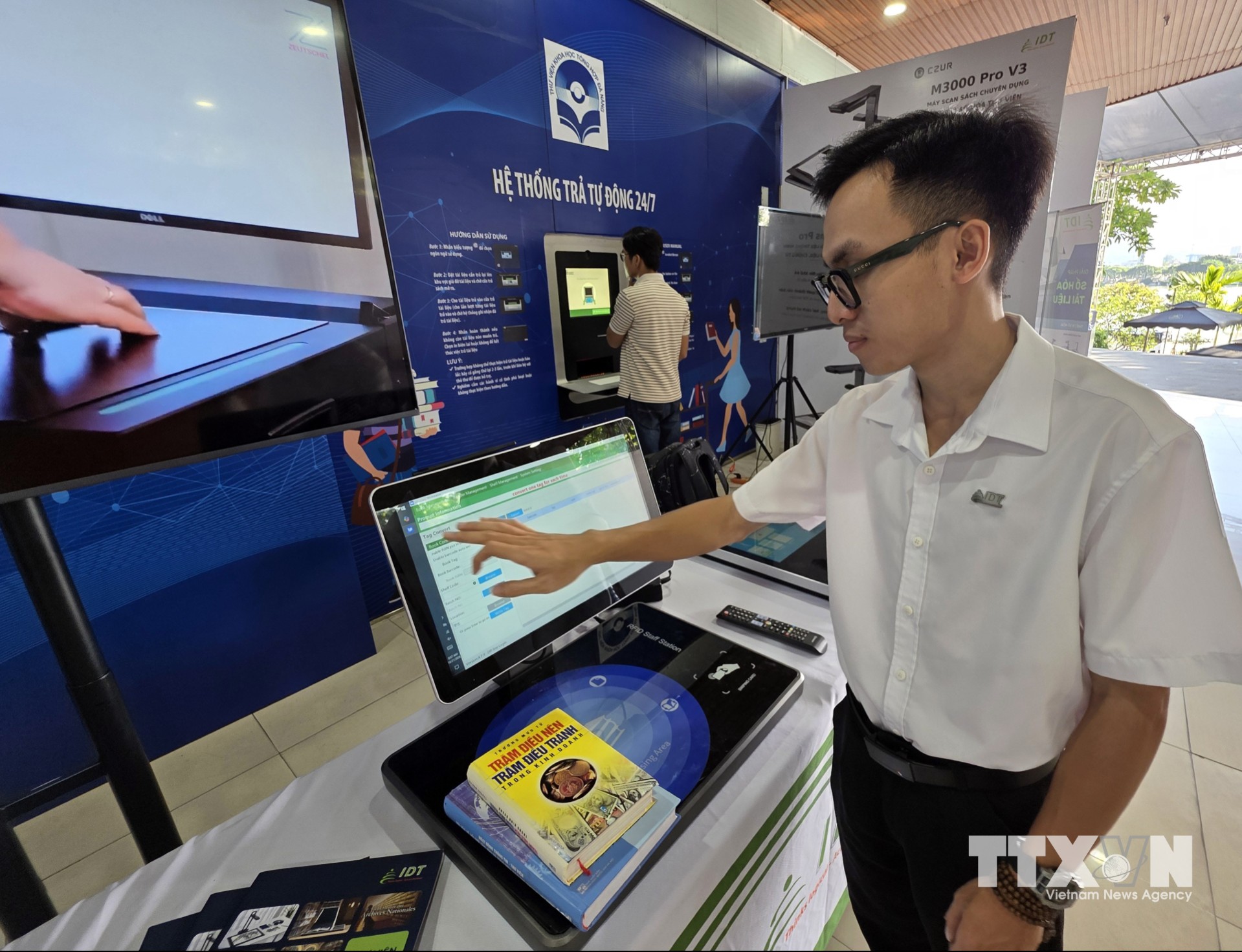 Nhân viên doanh nghiệp công nghệ giới thiệu giải pháp quản lý, mượn và trả sách thông minh tại không gian trưng bày công nghệ thư viện. (Ảnh: Trần Lê Lâm/TTXVN)